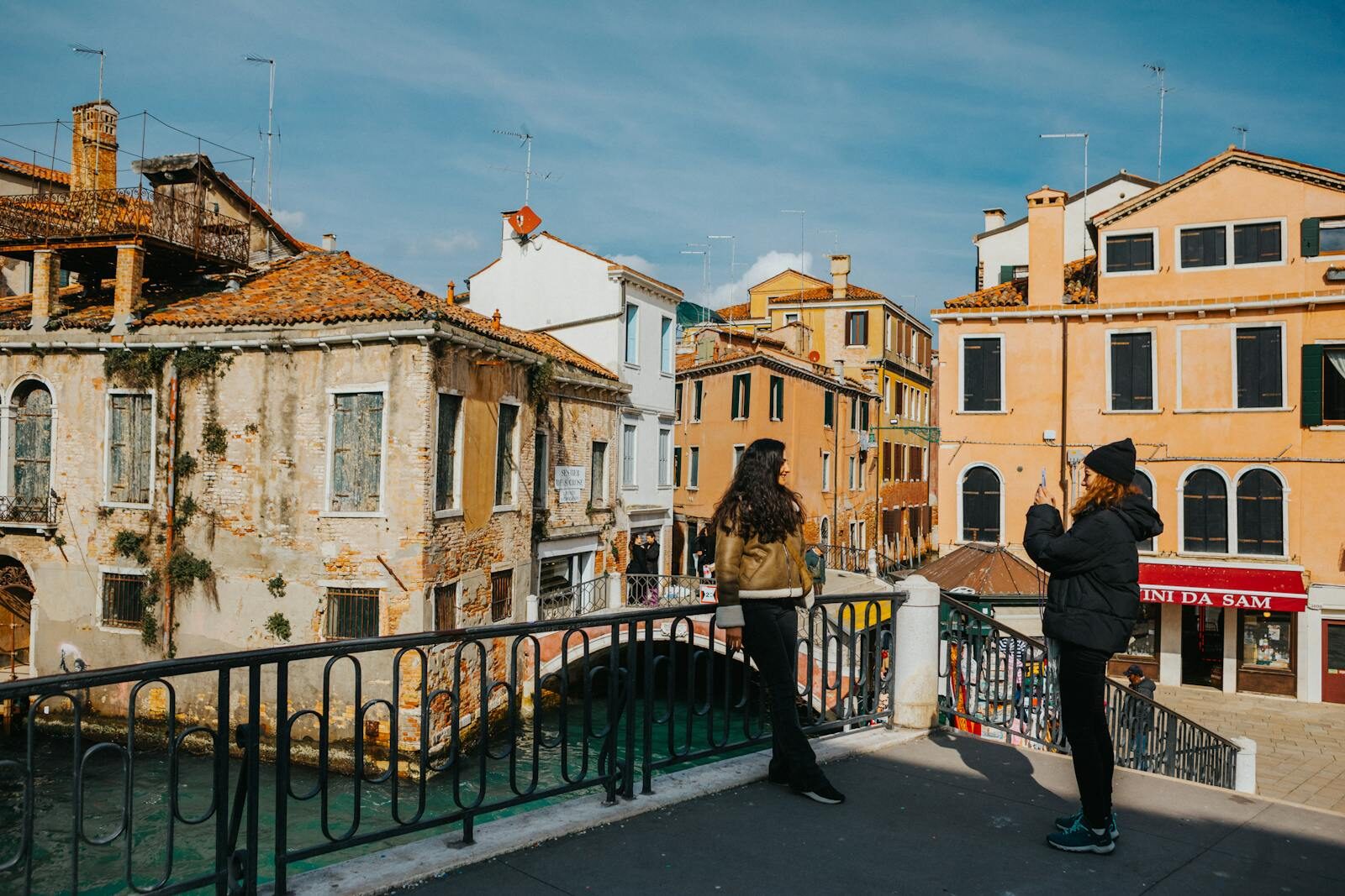 Two tourists admire the scenic architecture and waterways of Venice, Italy on a sunny day.